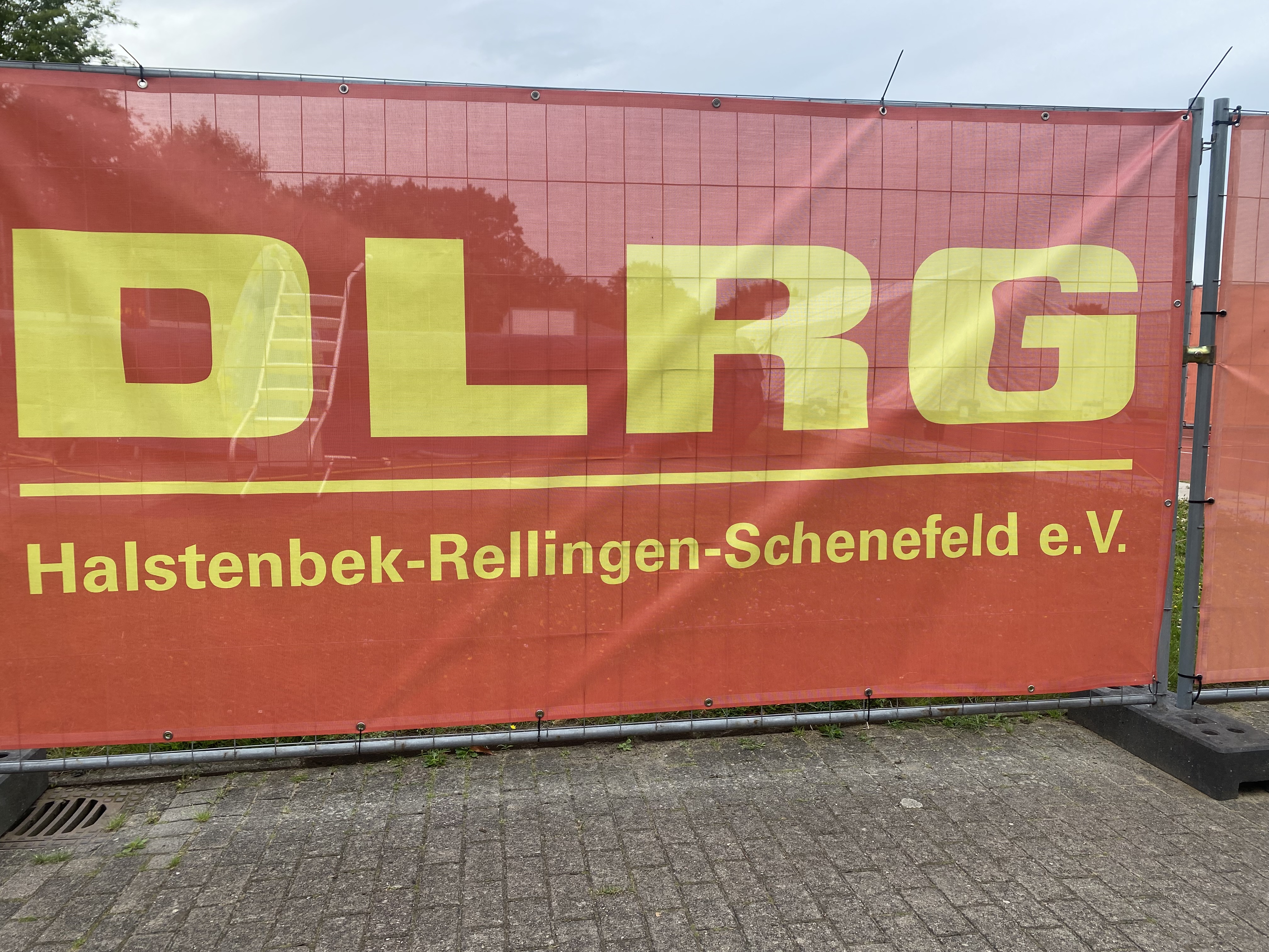 DLRG Banner. Im Hintergrund schimmert der große Schwimmlern-Pool durch