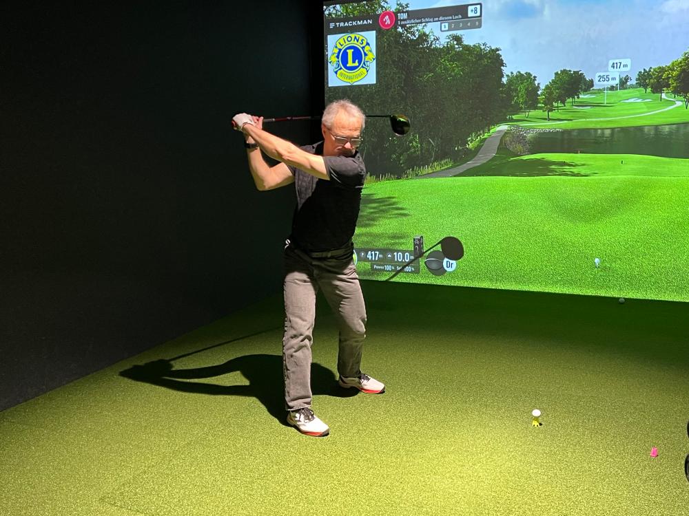 Turnierteilnehmer beim Abschlag auf die virtuelle Bahn